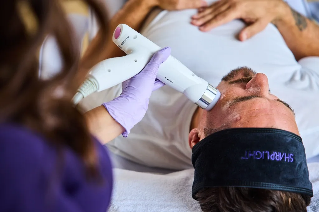 Close-up of RF face handpiece contouring a patient cheek with conductive gel