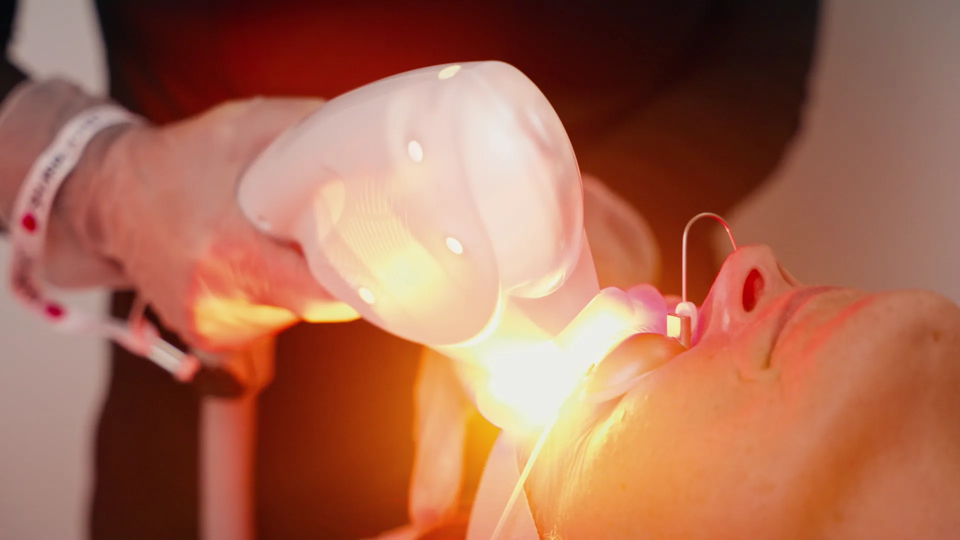 Practitioner delivering an OmniMax S4 facial light treatment with protective eyewear in place